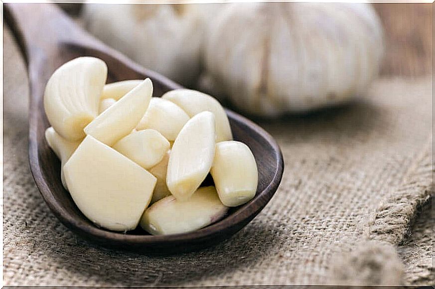 Wooden spoon with peeled garlic cloves.