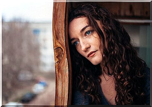 Pensive and sad woman looking out the window,