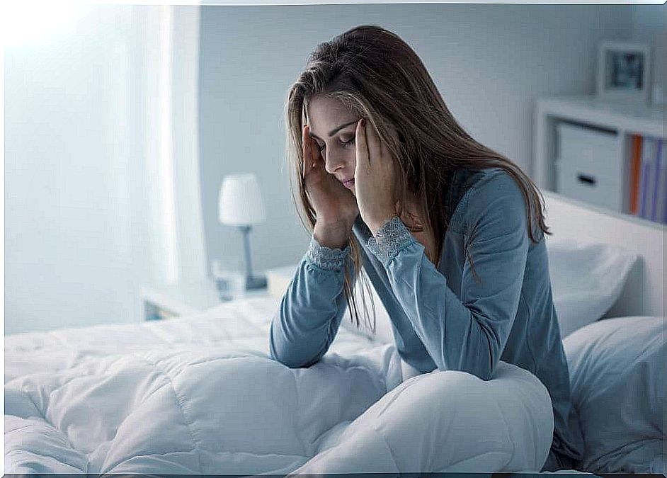 Woman in bed with her hands on her head.