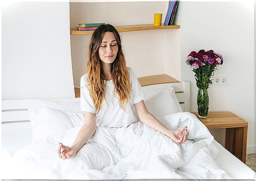 Relaxed woman meditating on her bed.