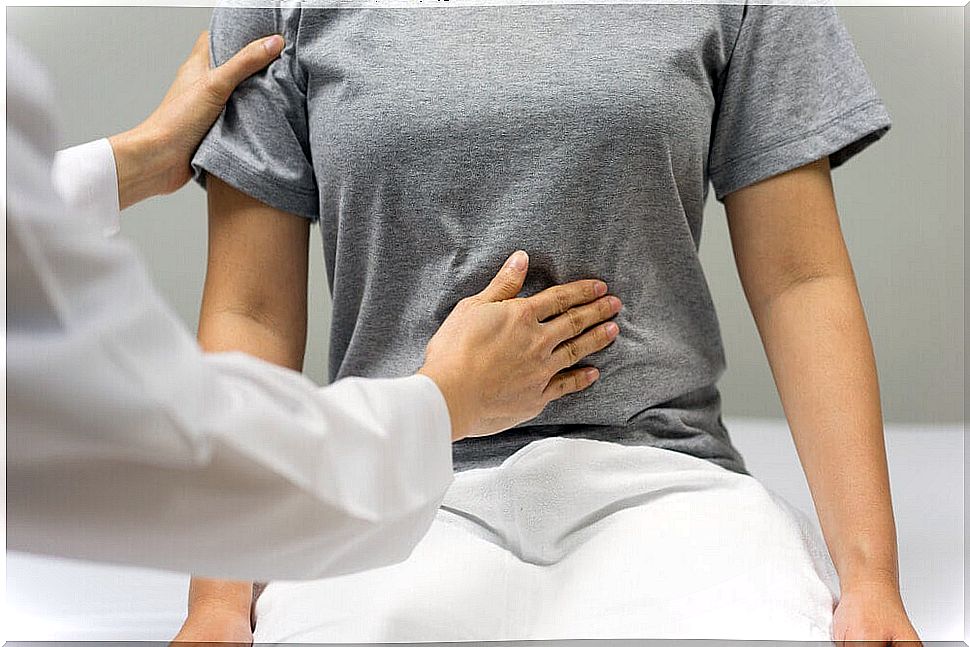 Doctor putting a hand on the abdomen of a patient.